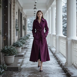 Peut inclure: Un long manteau prune à double boutonnage avec une ceinture assortie. Le manteau présente un revers classique et descend jusqu'aux chevilles. La personne porte des talons noirs et marche sur une allée enneigée.