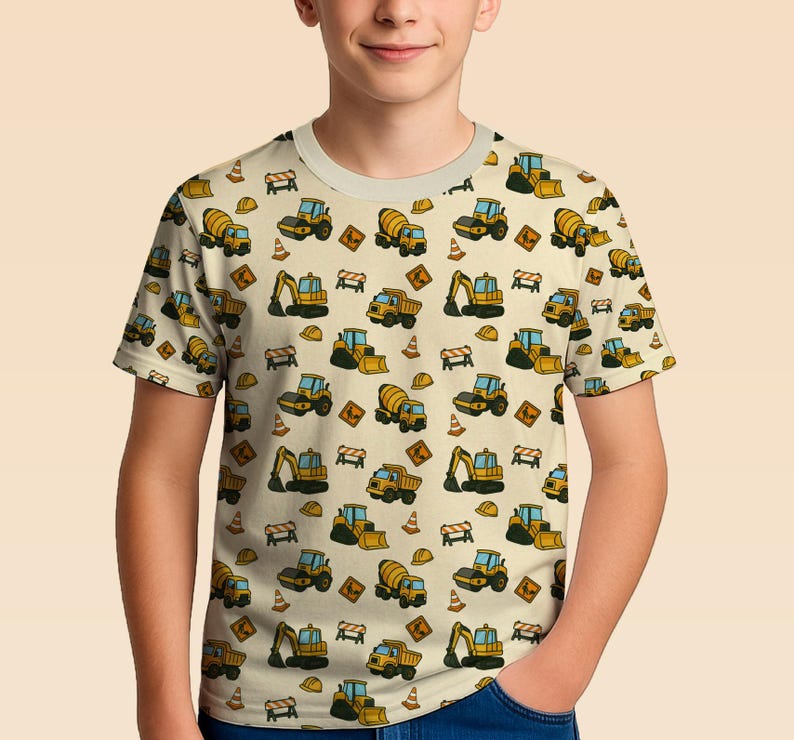 May include: A short-sleeved t-shirt with a repeating pattern of yellow and black construction vehicles, such as excavators and cement mixers, on a beige background. The design includes safety cones and road signs.