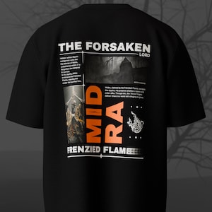 May include: Black t-shirt with a graphic design featuring the text "THE FORSAKEN LORD" and "MIDRA FRENZIED FLAME". The design includes an illustration of a figure and text blocks with additional details.