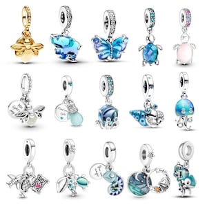Könnte beinhalten: Eine Sammlung von Silberanhängern mit verschiedenen Designs, darunter eine Biene, ein Elefant, ein Schmetterling, eine Schildkröte und eine Qualle. Die Anhänger verfügen über farbigen Emaille und funkelnde Akzente, ideal für Armbänder oder Halsketten.