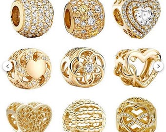 May include: Nine gold-toned charm beads with various designs. Some are encrusted with clear crystals, while others feature heart and floral patterns. One charm has the words "Love You" engraved on it.
