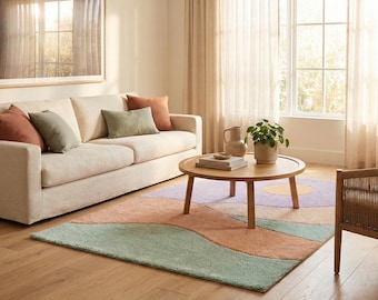 May include: A living room scene featuring a beige sofa with colorful throw pillows, a round wooden coffee table, and two woven armchairs. A patterned rug in pastel colors adds a decorative touch. A framed artwork hangs on the wall.