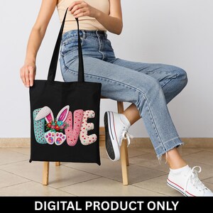 Könnte beinhalten: Schwarze Tragetasche mit dem Wort "LOVE" in farbenfrohen, strukturierten Buchstaben. Das "O" ist durch Hasenohren und ein Blumenarrangement ersetzt. Der Text "DIGITAL PRODUCT ONLY" befindet sich unten.