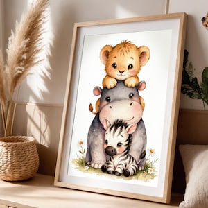 Puede incluir: Una impresión en acuarela enmarcada que presenta un cachorro de león, un hipopótamo y una cebra. Los animales están apilados, con el cachorro de león en la parte superior. El hipopótamo está en el medio y la cebra en la parte inferior. La impresión tiene un marco de madera clara.