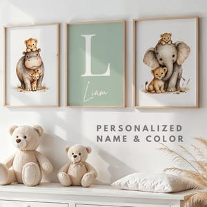 Peut inclure: Trois impressions d'art encadrées pour chambre d'enfant. L'une représente un hippopotame avec une girafe et un lionceau, une autre la lettre "L" et le nom "Liam", et la troisième un éléphant avec un lionceau et un léopard. Le texte "PERSONNALISÉ NOM & COULEUR" est en dessous.
