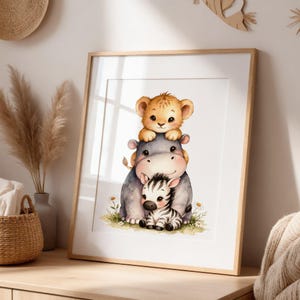 Puede incluir: Una impresión en acuarela enmarcada que presenta un cachorro de león, un hipopótamo y una cebra apilados uno encima del otro. Los animales están representados en colores suaves con un estilo caprichoso. La impresión está enmarcada en un marco de madera clara.