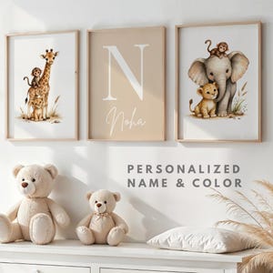 Peut inclure: Trois impressions d'art encadrées pour chambre d'enfant. L'une représente une girafe avec un singe et un lionceau, une autre une grande lettre "N" avec le nom "Noha", et la troisième un éléphant, un singe et un lionceau. Le texte "PERSONNALISÉ NOM & COULEUR" est en dessous.