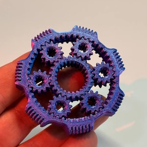 Può includere: Un complesso meccanismo a ingranaggi multistrato nei toni del blu e del viola. Gli ingranaggi sono finemente progettati e si incastrano, creando una struttura meccanica visivamente accattivante. L'oggetto è probabilmente stampato in 3D.