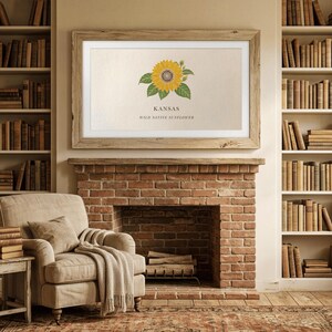 May include: A framed print featuring a sunflower illustration with the text "KANSAS WILD NATIVE SUNFLOWER." The artwork is displayed above a brick fireplace, with bookshelves on either side. A beige armchair and a side table are in the foreground.