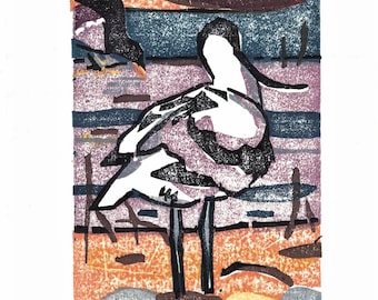 May include: A woodblock print of a bird standing on a beach with a sunset in the background. The bird is white with black markings and has long legs. The print is signed "Y+Ameet+Noodle at Herne 2019 Kay"