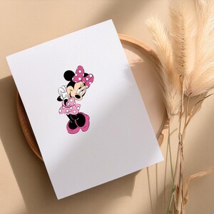 May include: A white card featuring a cartoon illustration of Minnie Mouse. Minnie Mouse is depicted in a classic pose, wearing a pink polka-dot dress, bow, and shoes. The image is set against a neutral background with decorative elements.