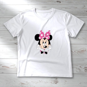 May include: White t-shirt featuring a graphic of Minnie Mouse. Minnie Mouse is depicted with black ears, a pink polka-dot bow, and a smiling face. The shirt is made of a soft, lightweight material, perfect for casual wear.