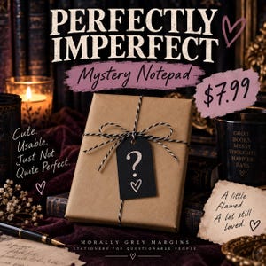 May include: A rectangular notepad wrapped in brown paper with black and white twine and a black tag featuring a white question mark and heart. The text reads PERFECTLY IMPERFECT Mystery Notepad, Cute. Usable. Just Not Quite Perfect., A little Flawed. A lot still loved., and MORALLY GREY MARGINS STATIONERY FOR QUESTIONABLE PEOPLE.