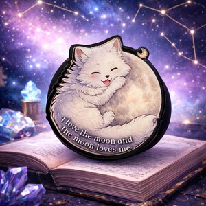 May include: A white cat hugging a moon, with the text "I love the moon and the moon loves me." The image is set against a starry night sky. The cat is smiling and the moon is a light beige color.