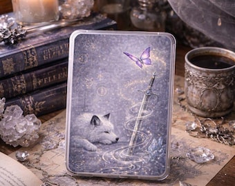 May include: A clear phone case featuring a fantasy illustration. The design includes a sleeping white wolf, a purple butterfly, and a sword with a swirling magical effect. The background is a starry, purple-toned scene.
