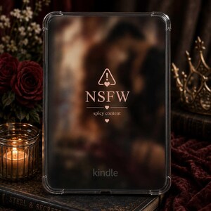 Könnte beinhalten: Eine transparente Schutzhülle für einen Kindle E-Reader mit einem aufgedruckten Design in der Mitte. Das Design zeigt ein Warndreieck mit einem Ausrufezeichen und einem Herz, den Text "NSFW" sowie den Text "spicy content" mit kleinen Herzen.