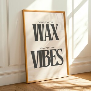 Puede incluir: Un p&oacute;ster rectangular en un marco de madera clara con fondo color crema y texto gris oscuro. El texto dice "COME FOR THE WAX" en la parte superior y "STAY FOR THE VIBES" en la parte inferior con una tipograf&iacute;a serif audaz.