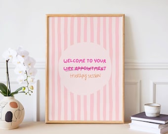 May include: A framed print with a pink striped background and a light pink circle in the center. The text reads "Welcome to your wax appointment therapy session" in pink and orange lettering. The frame is light brown.
