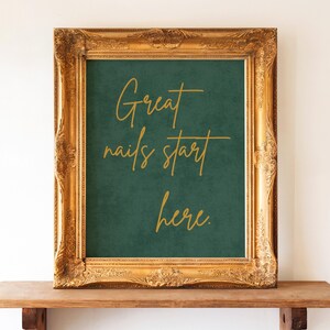 Puede incluir: Impresión enmarcada con el texto "Great nails start here" en letras doradas sobre un fondo verde oscuro. El marco dorado adornado añade un toque de elegancia a la decoración temática de uñas.