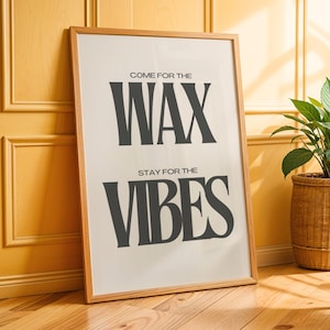 Puede incluir: Un cuadro rectangular con marco que presenta un fondo blanco con texto negro en negrita que dice COME FOR THE WAX y STAY FOR THE VIBES. La impresi&oacute;n est&aacute; encerrada en un marco de madera de tono claro y descansa sobre un suelo de madera.