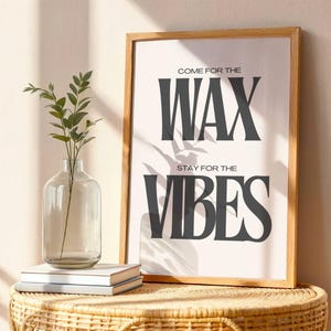 Puede incluir: Un cuadro vertical enmarcado con el texto negro COME FOR THE WAX STAY FOR THE VIBES en una fuente serif negrita sobre fondo blanco. El marco de madera es de color marr&oacute;n claro y la l&aacute;mina se muestra junto a un jarr&oacute;n de cristal.