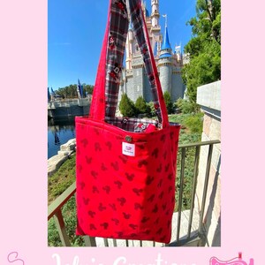 May include: Red tote bag with black Mickey Mouse silhouettes. The bag has a plaid lining and long straps. The text "Inside" is at the top. The bag is displayed in front of a castle.