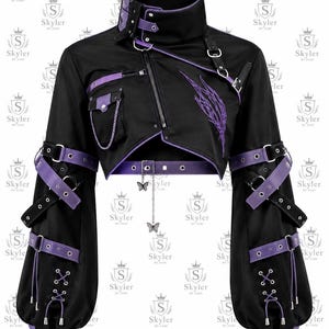 Puede incluir: Una chaqueta corta negra con detalles en morado, cuello alto con correa de hebilla y cremallera asimétrica. Las mangas tienen múltiples correas con hebillas y detalles de cordones. Una cadena plateada con dijes de mariposa cuelga del dobladillo.