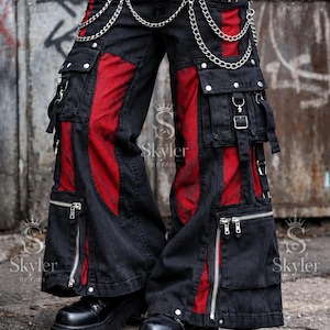 Puede incluir: Pantalones cargo negros con paneles de malla roja, múltiples bolsillos utilitarios, cremalleras de metal plateado y una cadena decorativa drapeada en la parte delantera. Se llevan con un cinturón de tachuelas y botas de plataforma.