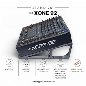 Puede incluir: Un soporte negro para una mesa de mezclas Xone:92, inclinado a 20 grados. Cuenta con almohadillas de goma antideslizantes y varillas de conexión de madera de haya. El texto "XONE:92" y "JRS136DESIGN" es visible.