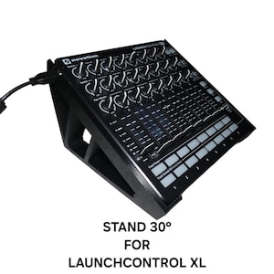 May include: A black wooden stand angled at 30 degrees, designed for a Novation LaunchControl XL. The stand supports the electronic music production controller, which has knobs, faders, and buttons. The text "STAND 30° FOR LAUNCHCONTROL XL" is visible.