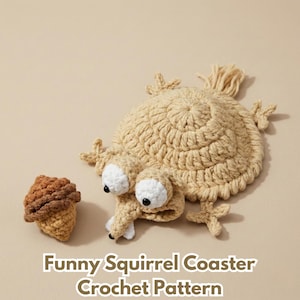 Peut inclure: Un dessous de verre en forme d'écureuil et un gland crochetés, beiges et bruns. L'écureuil a de grands yeux blancs et un long museau. Le texte "Funny Squirrel Coaster Crochet Pattern" est en bas de l'image.