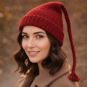 Peut inclure: Un bonnet rouge tricoté avec une longue queue tressée et une gland. Le chapeau est de couleur rouge foncé et semble fait à la main. C'est un accessoire d'hiver.