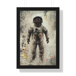 May include: Framed art print featuring an astronaut in a spacesuit. The artwork has a textured, abstract style with scribbled lines and splashes of color. The astronaut is centered, with a white helmet and suit, set against a muted background.