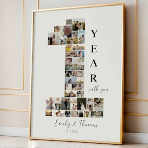 Può includere: Stampa incorniciata con un collage di foto a forma di numero uno. Il testo "YEAR with you" è visibile. I nomi "Emily & Thomas" e la data "11.4.2028" sono scritti sotto. La cornice è dorata.