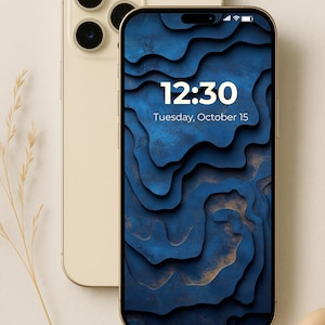 May include: Two gold-colored smartphones, one displaying a blue and gold abstract design on its screen. The screen shows the time 12:30 and the date Tuesday, October 15. The phone on the left has three camera lenses.