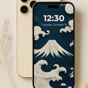 Könnte beinhalten: Goldenes Smartphone mit einem Bildschirm, der ein japanisch inspiriertes Design mit Berg, Wellen und Wolken in Weiß auf dunkelblauem Hintergrund zeigt. Die Uhrzeit 12:30 und das Datum sind sichtbar. Ein weiteres goldenes Telefon befindet sich dahinter.