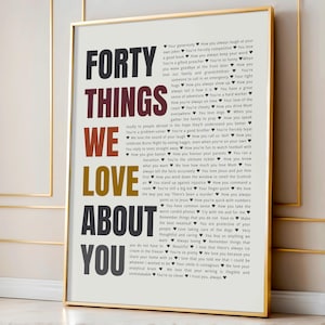 May include: A framed vertical poster with a white background featuring the text FORTY THINGS WE LOVE ABOUT YOU in large, stacked, multi-colored letters. To the right, forty distinct phrases are listed, each separated by a small black heart icon.