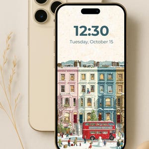 Könnte beinhalten: Ein goldenes iPhone mit einem winterlichen Stadtbild von bunten Reihenhäusern und einem roten Doppeldeckerbus. Der Bildschirm zeigt die Uhrzeit 12:30 Uhr und das Datum Dienstag, 15. Oktober. Ein zweites goldenes iPhone ist sichtbar.