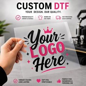 May include: A clear transfer sheet featuring the text Your Logo Here in black and pink lettering with a pink crown icon above the text and small star accents. The sheet is held up against a background with text reading CUSTOM DTF.