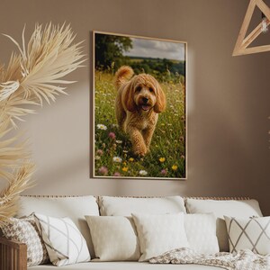 Puede incluir: Una impresión de arte mural enmarcada que muestra a un perro doodle de color marrón dorado caminando por un campo de hierba verde y pequeñas flores silvestres blancas, amarillas y moradas bajo un cielo nublado. El perro tiene pelo rizado y orejas caídas.
