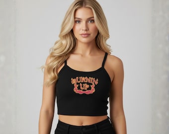 May include: A black ribbed crop top with thin spaghetti straps featuring the text BURNIN UP printed in a stylized orange and red font with flame-like decorative borders centered on the chest area of the garment.
