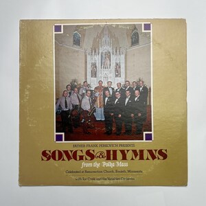 May include: Vintage vinyl record album cover with a gold background and a photograph of a group of men in suits and formal wear. The album title is "SONGS & HYMNS from the Polka Mass". The album cover is slightly worn.