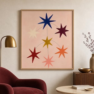 May include: A square framed wall art piece featuring a light pink background with seven eight-pointed stars in various colours including dark blue, deep red, yellow, orange, light pink, cream, and dark purple, connected by thin black lines.