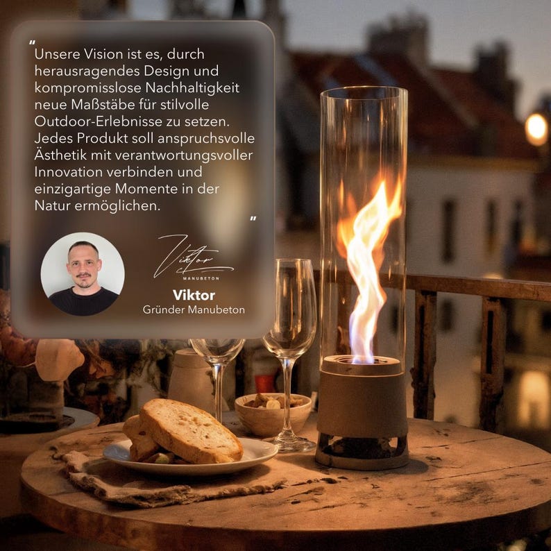 May include: A small outdoor tabletop fireplace with a tall glass cylinder, showcasing a vibrant flame. The scene includes a wooden table set with bread, wine glasses, and a small bowl. Text in the image reads: "Unsere Vision ist es..." and "Viktor, Gr&uuml;nder Manubeton."