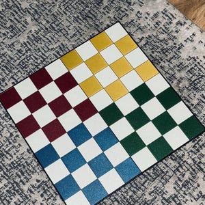 May include: A colorful checkerboard with squares in red, gold, green, and blue, alternating with white squares. The board is set on a patterned gray surface, suggesting a game or decorative item.