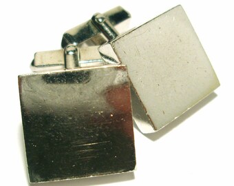 May include: A pair of silver cufflinks with square faces. The cufflinks are made of metal and have a polished finish.
