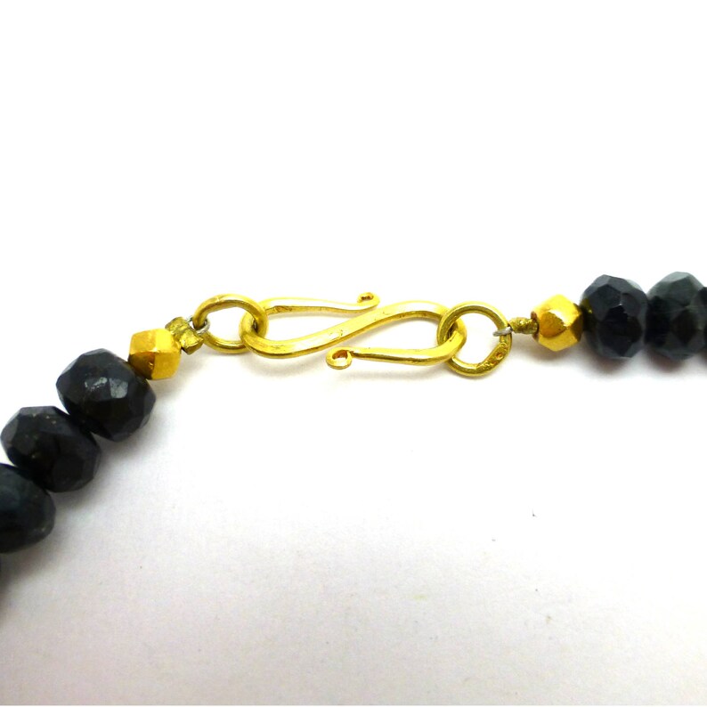 May include: A gold clasp with a black beaded necklace. The clasp is a simple, elegant design with a smooth finish.