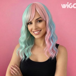Op de afbeelding: Een vrouw met een kleurrijke pruik met roze, blauwe en mintgroene tinten. De pruik heeft lang, golvend haar met pony. De vrouw draagt een zwarte tanktop en glimlacht. De achtergrond is effen roze en het woord "WIGCO" is zichtbaar.