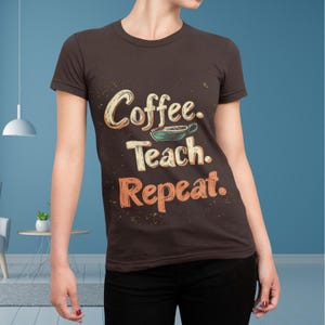 Könnte beinhalten: Braunes T-Shirt mit dem Text "Coffee. Teach. Repeat." im Vintage-Stil. Das Design beinhaltet eine Kaffeetasse. Das T-Shirt hat einen Rundhalsausschnitt und kurze Ärmel.