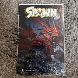 May include: Comic book cover featuring the title "SPAWN" in a stylized font. The artwork depicts a dark, action-packed scene with a red-caped figure and other creatures. The issue number "122" is visible.